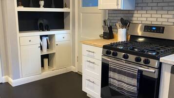 A modern kitchen with white cabinetry, a black and stainless steel stove, and a geometric patterned rug.