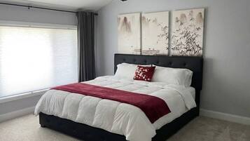 Une chambre à coucher avec un lit, une fenêtre avec des rideaux et trois tableaux accrochés au mur.