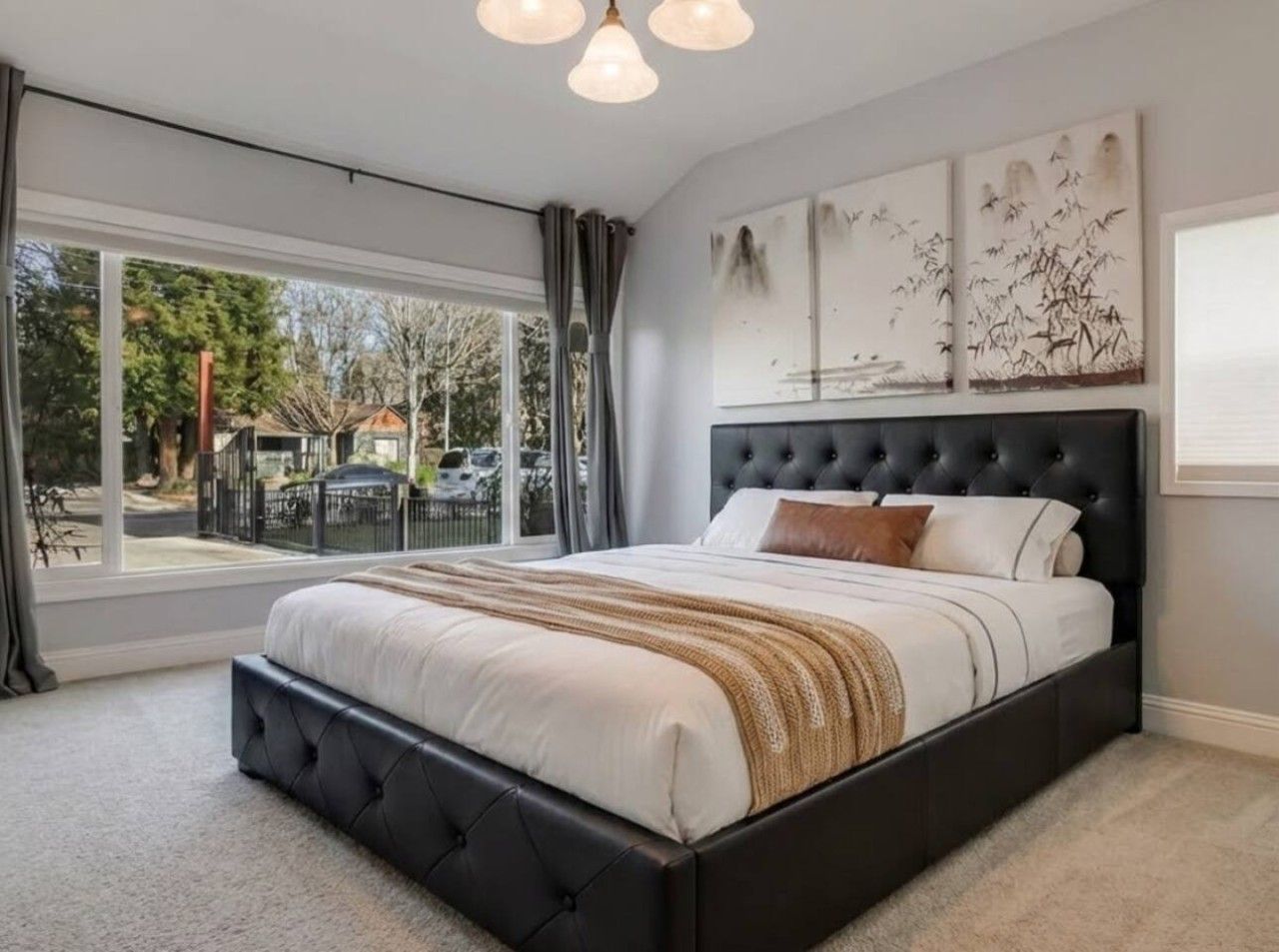 A bedroom with a large bed, a window with a view, and artwork on the wall.