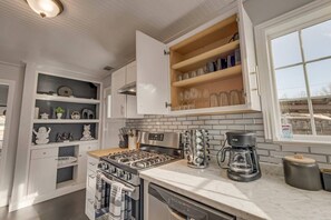 A modern kitchen with white cabinetry, a built-in stove, a coffee maker, and a window with a view. - Japanese-Style Retreat: Fountain, Hot Tub, Arcade (Chico)