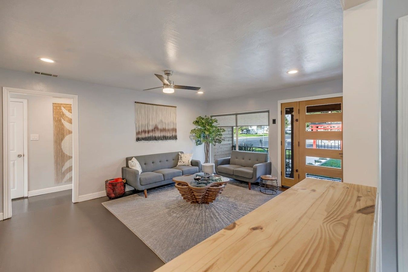 A modern living room with a grey sofa, a coffee table, and a ceiling fan.