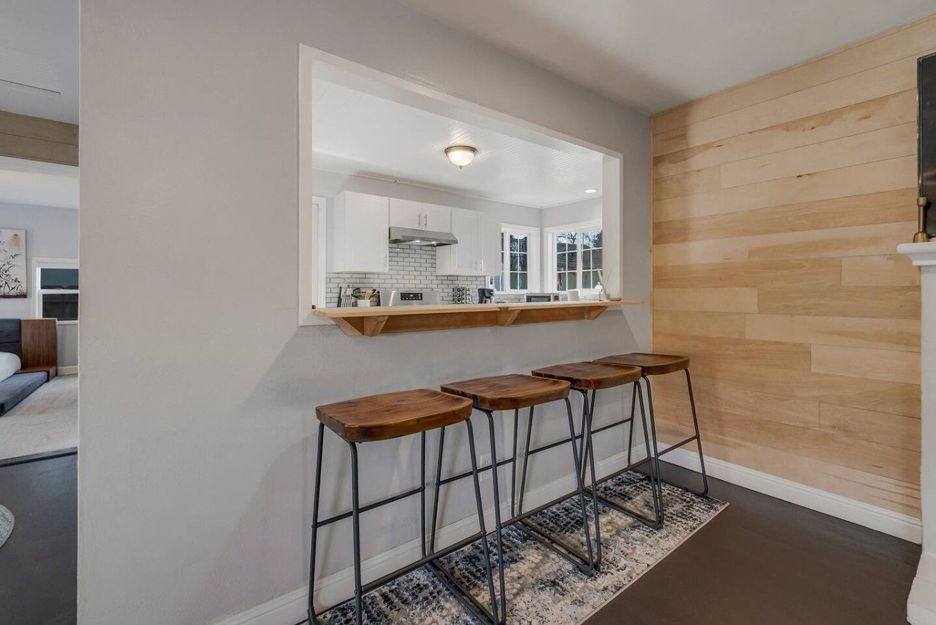 Une cuisine moderne avec un plan de travail en bois, un grand miroir et trois tabourets.