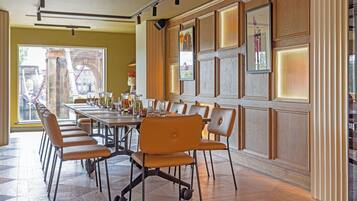 A conference room with a long table and multiple chairs, large windows with a view of a bridge, and wooden paneling on the walls.