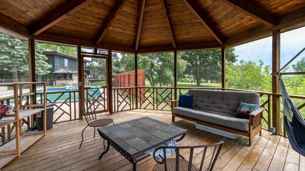 Un espace extérieur abrité, doté d’une terrasse en bois, d’un canapé, d’une table et de chaises.