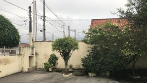 Ulkona oleva sisäpiha, jossa on betonilattia, ruukkukasveja ja taustalla punatiilikatolla varustettu rakennus.