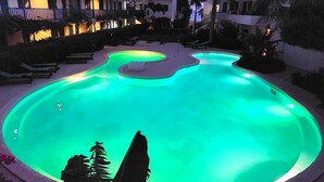 Una piscina de forma singular, envoltada de gandules i palmeres.