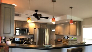 Una cocina moderna con electrodomésticos de acero inoxidable, armarios de madera e iluminación colgante.