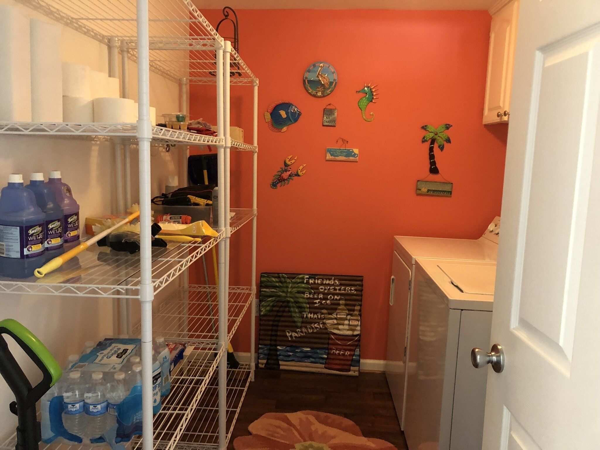 Een kleine keuken met een witte koelkast, een spoelbak en een plank met schoonmaakmiddelen.