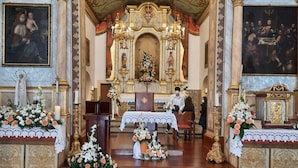An ornate church interior with a central altar, religious statues, and floral decorations. - Cottage/Gite Cavalinho (Calheta)