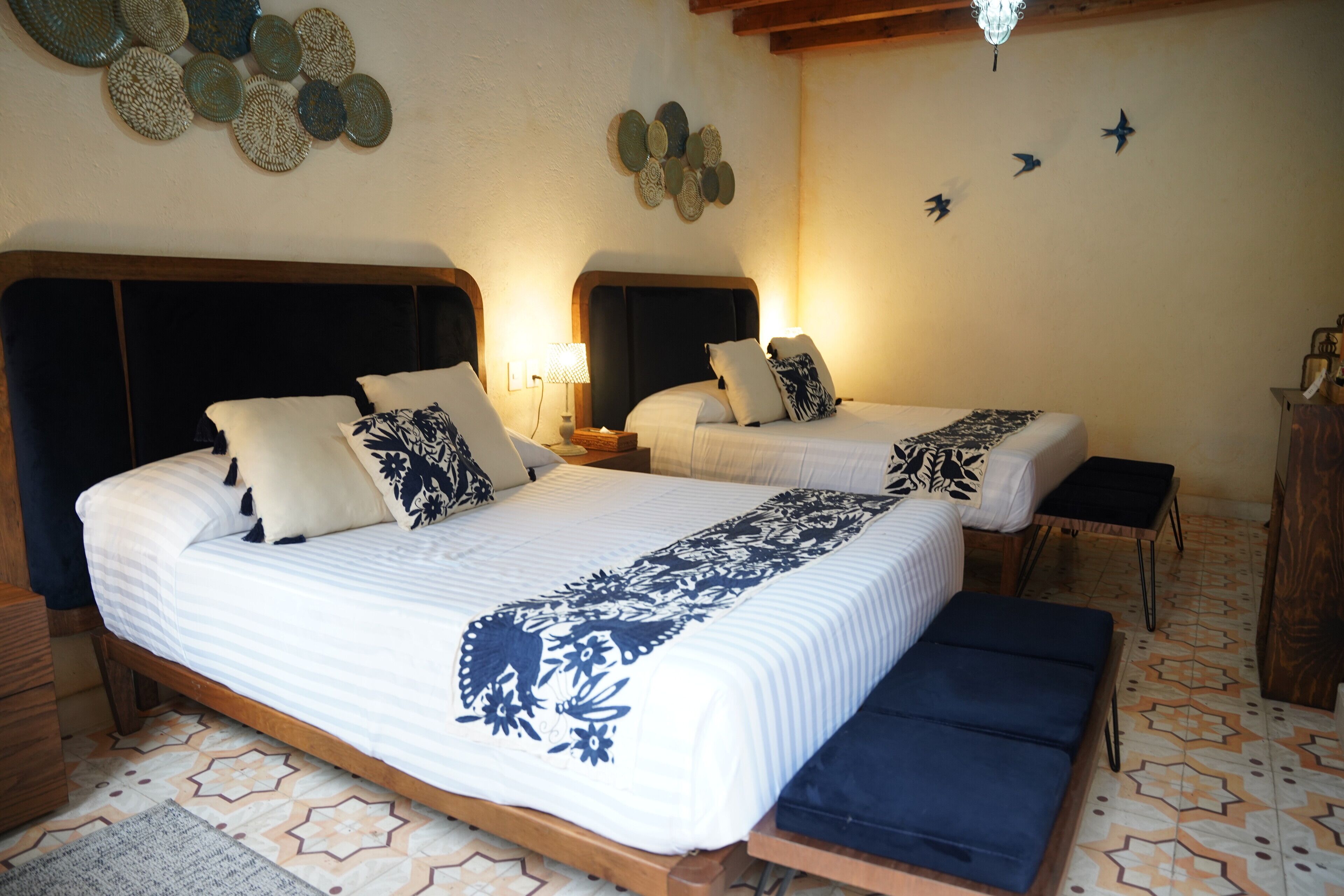 Un lit double avec une couvre-lit à motifs, une table de chevet avec une lampe et un banc.
