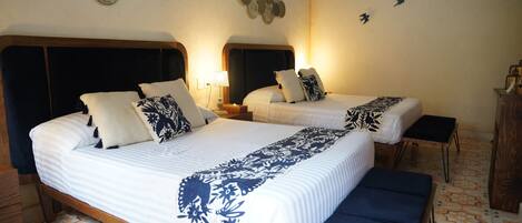 A double bed with a patterned bedspread, a bedside table with a lamp, and a bench.