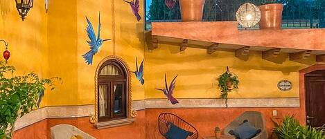 A courtyard with outdoor seating, a tree, and decorative wall art.