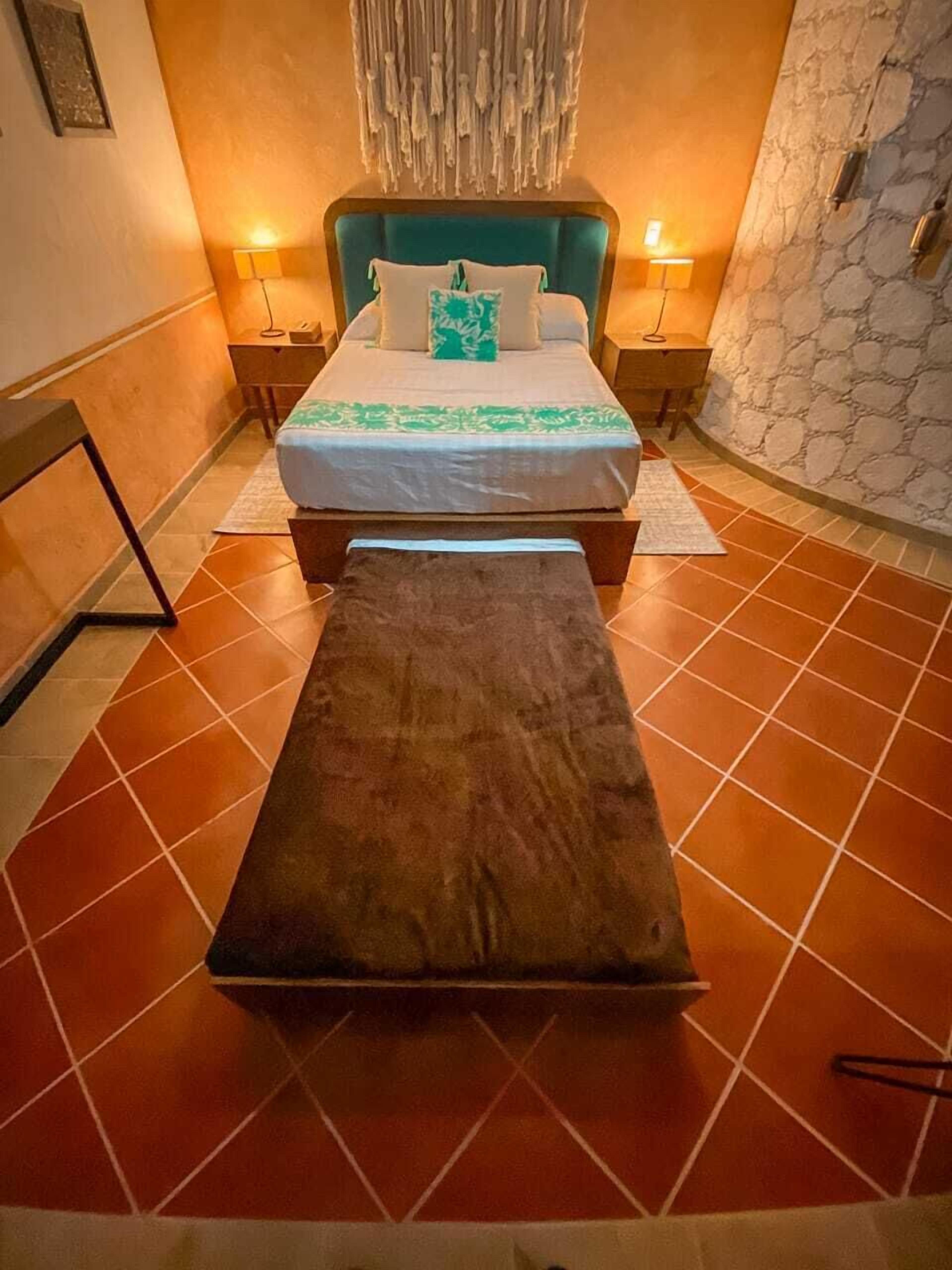 A bedroom with a bed, a bench, and a stone wall.