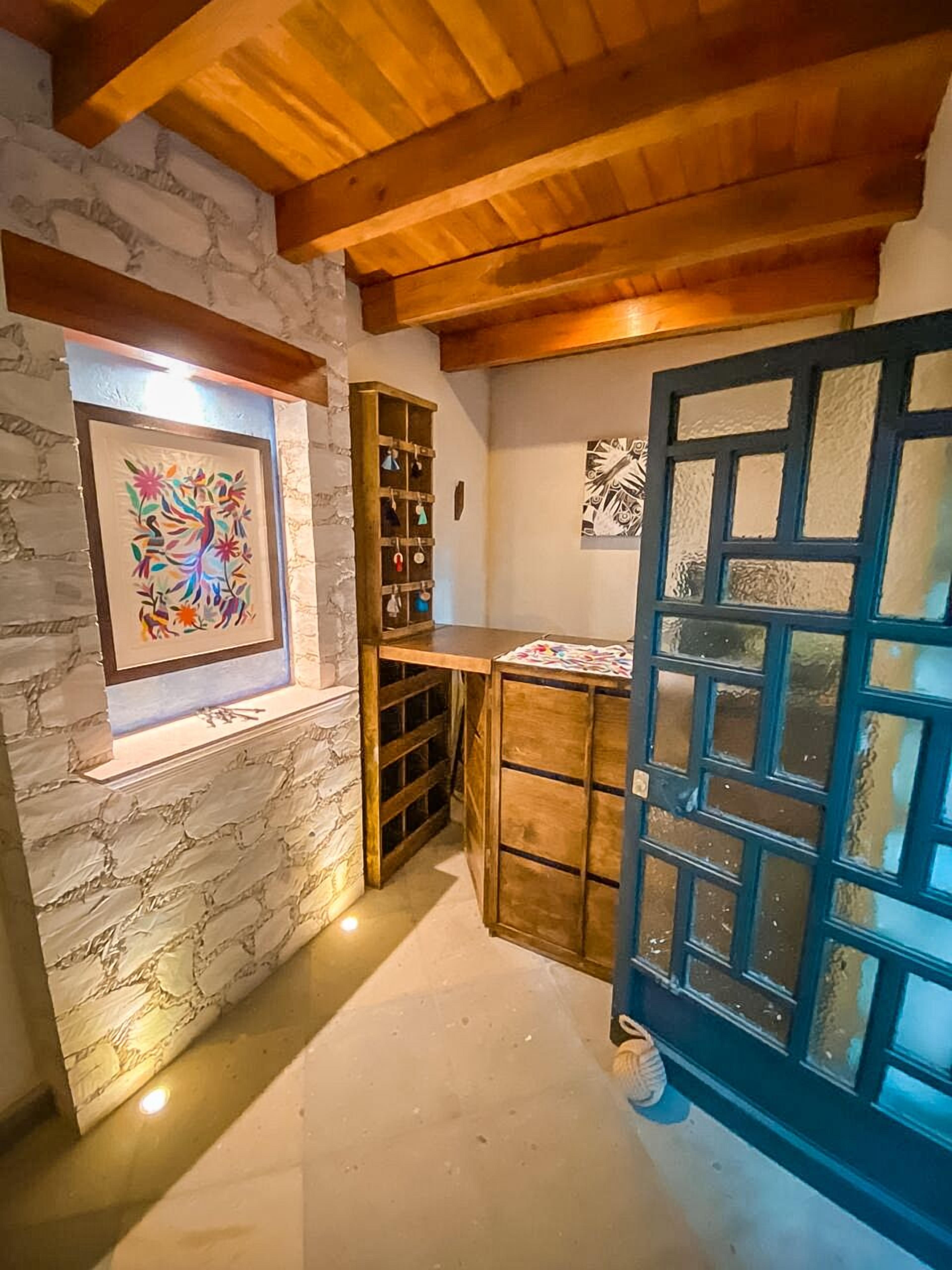 Ein Zimmer mit Steinwand, Holzbalkendecke, einem Holzschrank mit hängenden Gegenständen und einer Tür mit Gittermuster.
