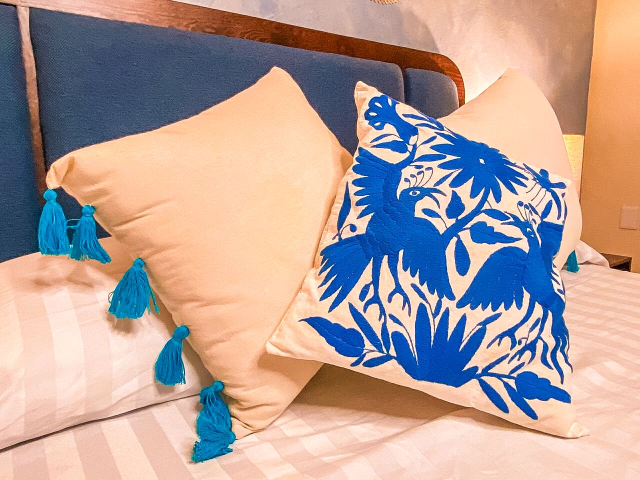 Una cama con ropa de cama a rayas y dos almohadas, una lisa y otra con un estampado floral azul.