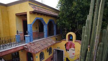 A building with a yellow facade, blue arches, and a staircase leading to a balcony.
