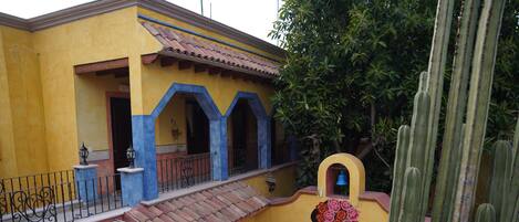 A building with a yellow facade, blue arches, and a staircase leading to a balcony.