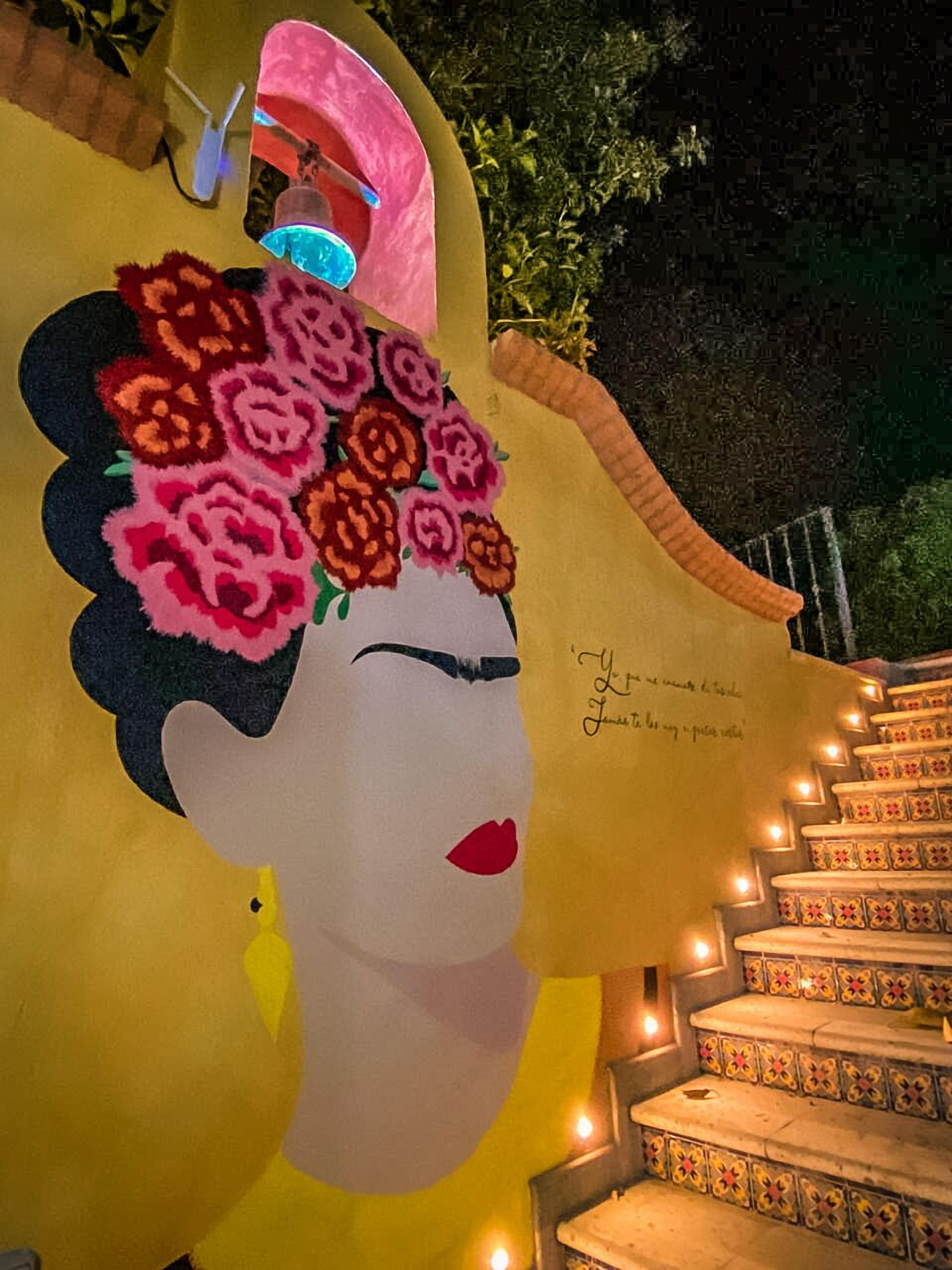 Eine große, beleuchtete Gesichtsskulptur mit floralen Mustern am Kopf und einer Treppe mit dekorativen Fliesen.
