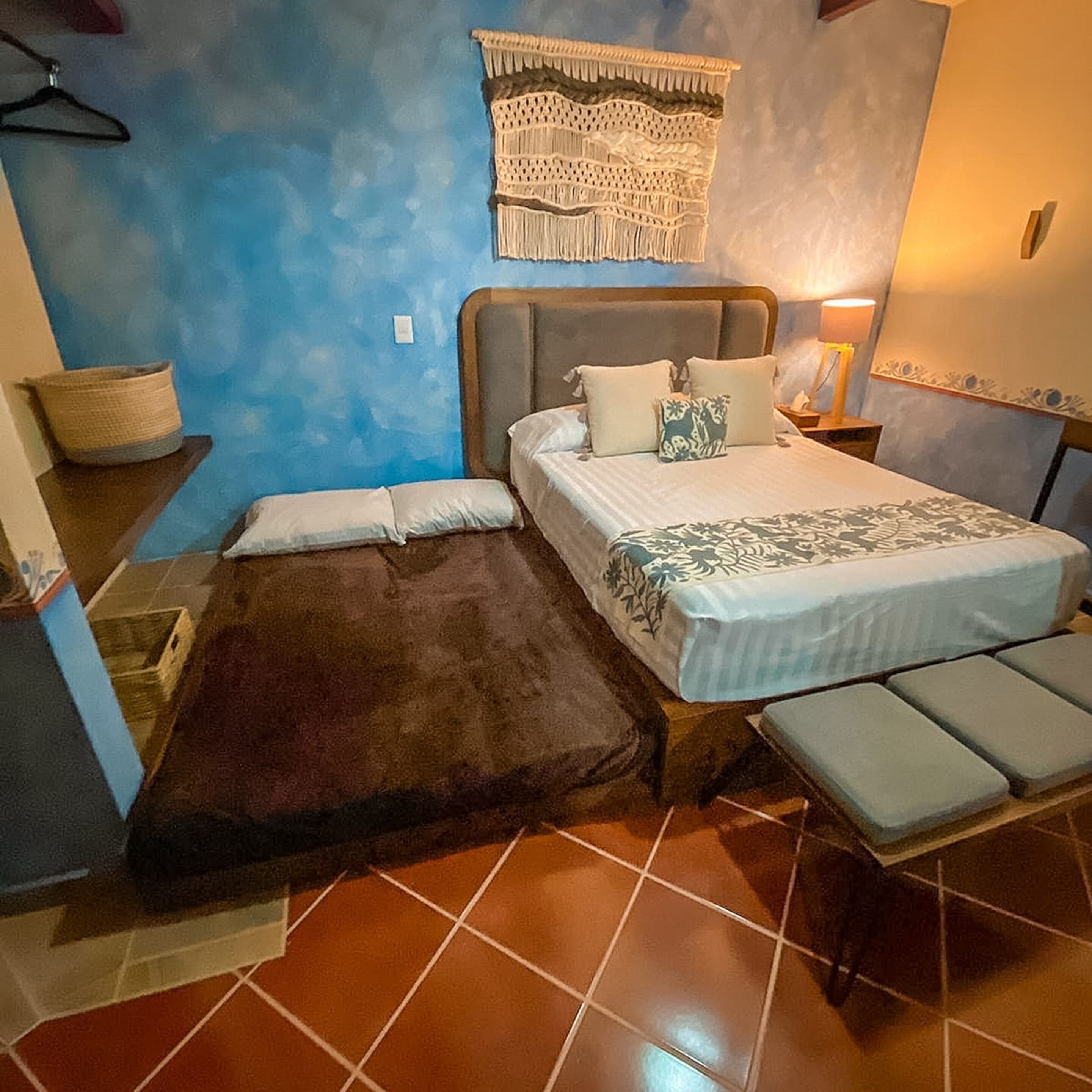 Una camera da letto con un letto, una panca, un decoro a parete e un comodino.