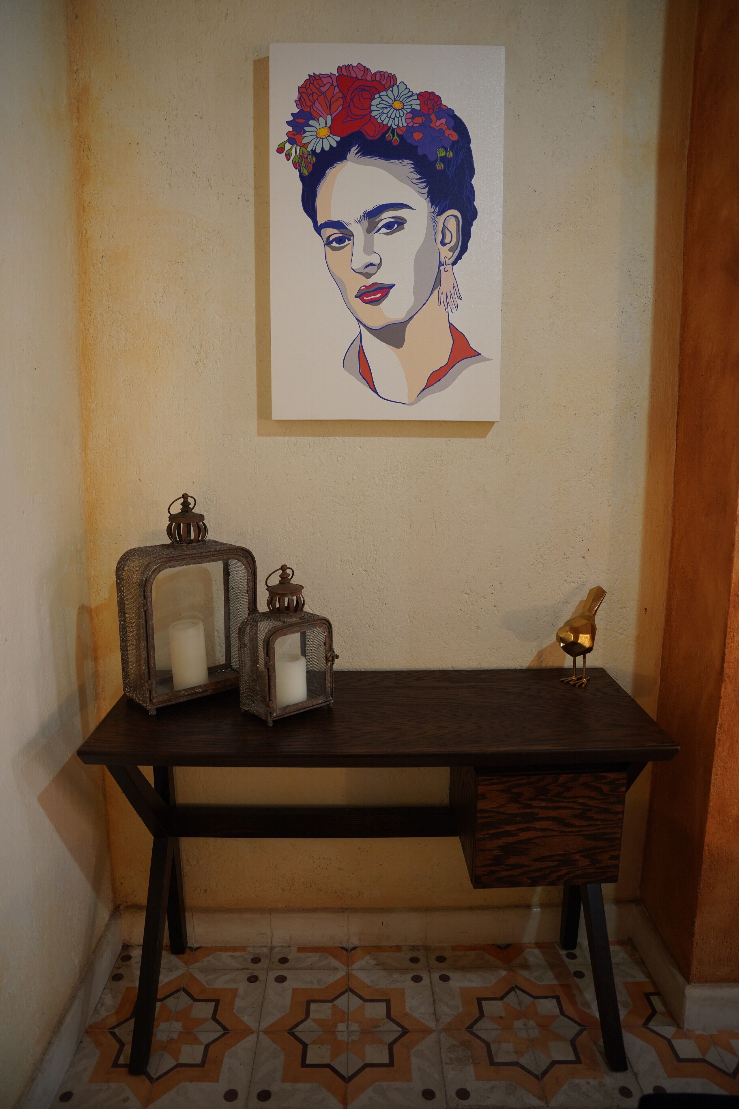 A room with a wooden desk, two lanterns, a small bird figurine, and a wall-mounted painting.