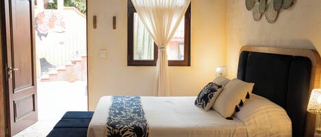 A bedroom with a bed, bedside table, lamp, and a window with curtains.