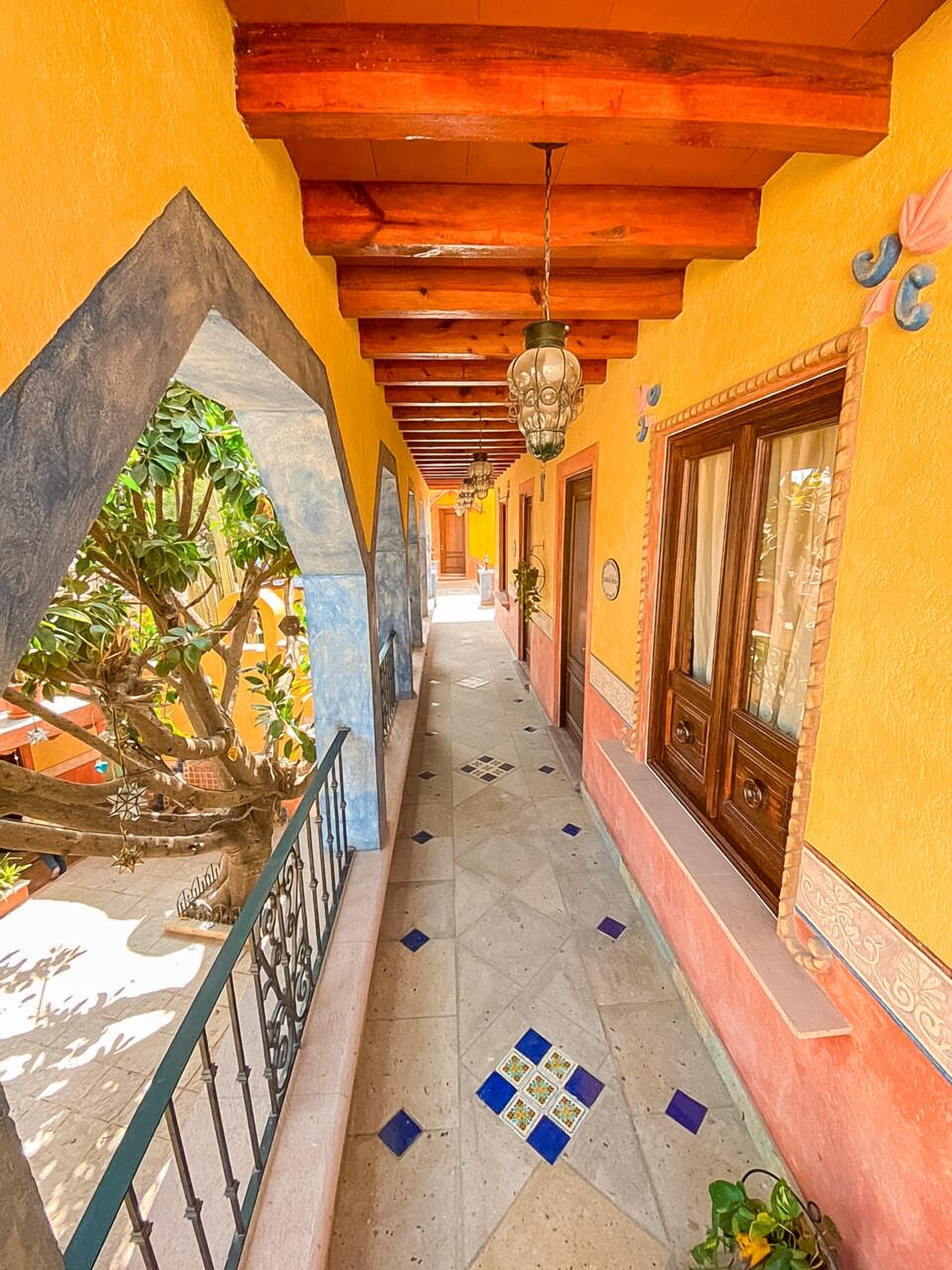 A corridor with a tiled floor, wooden beams, and hanging lanterns.