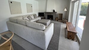 Una sala de estar moderna con un sofá modular gris, una chimenea y un ventanal que ofrece vistas al exterior.