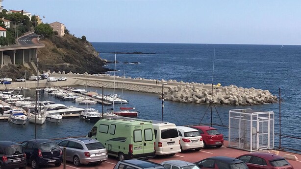A marina with parked cars and boats, a rocky shoreline, and a clear view of the sea. - Ideal apartment for three people (Cerbère)