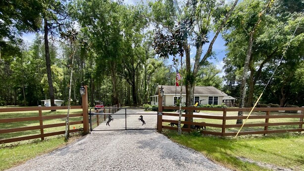 A gravel driveway leading to a gated area with a house and a fenced field. - Cozy Cottage - Close to Everything, Nature Lovers Dream! (Odessa)