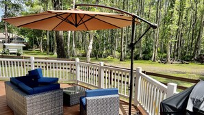A deck with wicker furniture and a large umbrella. - Cozy Cottage - Close to Everything, Nature Lovers Dream! (Odessa)