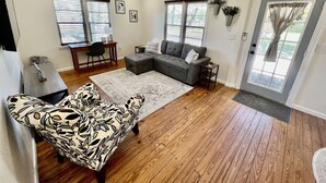 A living room with a sectional sofa, a patterned armchair, a coffee table, and a dining area with a table and chairs. - Cozy Cottage - Close to Everything, Nature Lovers Dream! (Odessa)