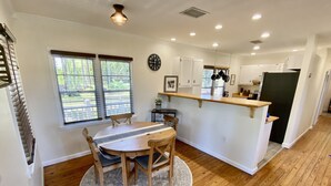 A compact kitchen with a dining area, wooden flooring, and a window with blinds. - Cozy Cottage - Close to Everything, Nature Lovers Dream! (Odessa)