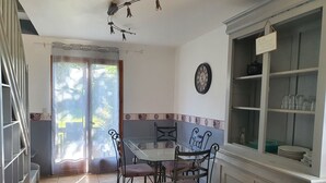 A dining area with a table and chairs, a clock on the wall, and a cabinet with glassware. - Comfortable 8-person house with shared heated pool between Sarlat and Cahors (Salviac)