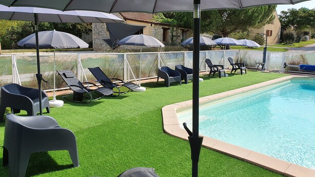 A poolside area with artificial grass, lounge chairs, and umbrellas. - Comfortable 8-person house with shared heated pool between Sarlat and Cahors (Salviac)