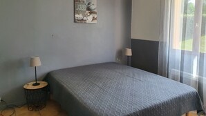 A bedroom with a bed, two bedside lamps, a wall-mounted picture, and a window with curtains. - Comfortable 8-person house with shared heated pool between Sarlat and Cahors (Salviac)