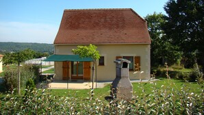 A two-story house with a red-tiled roof, a stone chimney, and a green awning. - Comfortable 8-person house with shared heated pool between Sarlat and Cahors (Salviac)