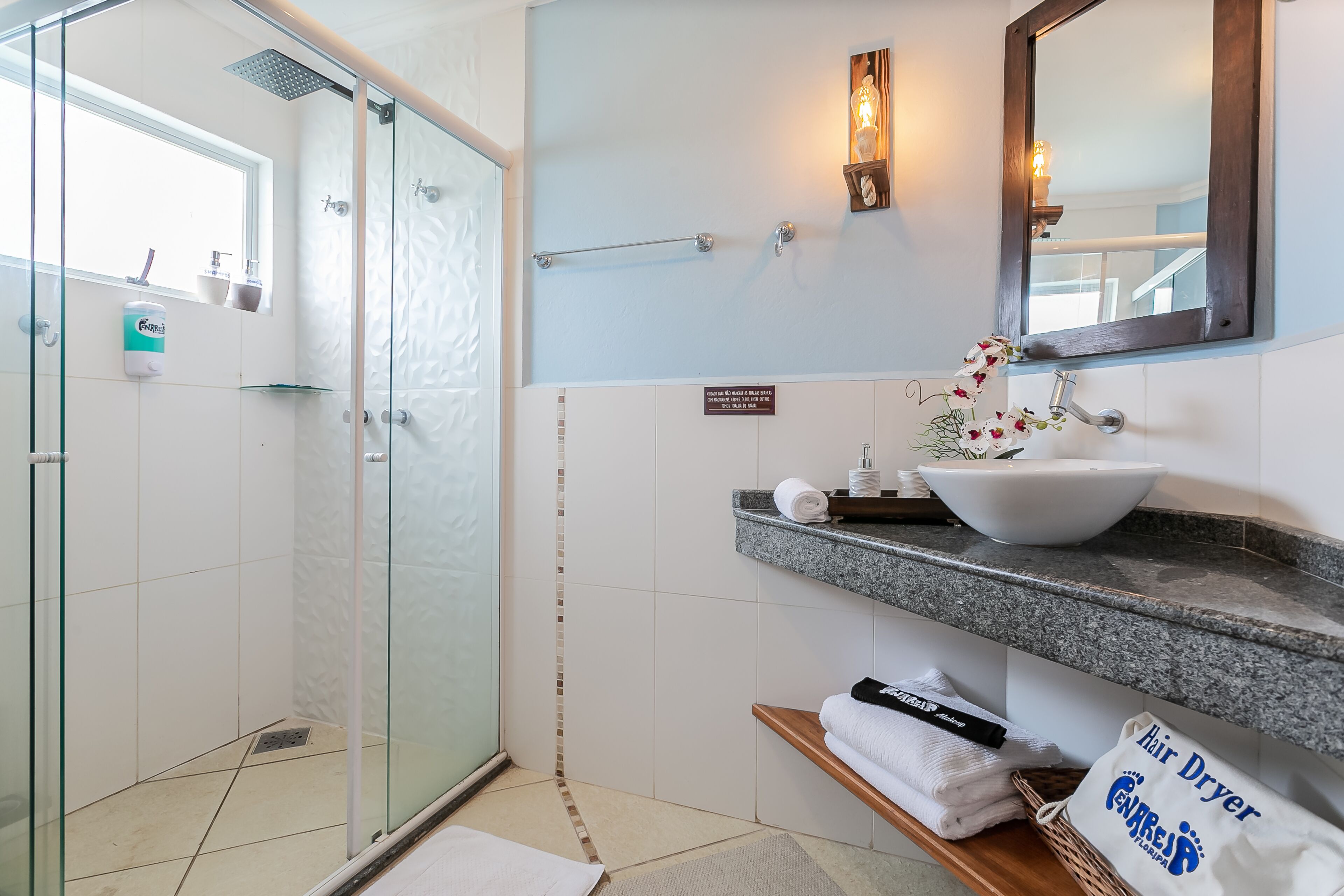 A bathroom with a glass shower enclosure, a white sink, a towel rack, and a mirror.