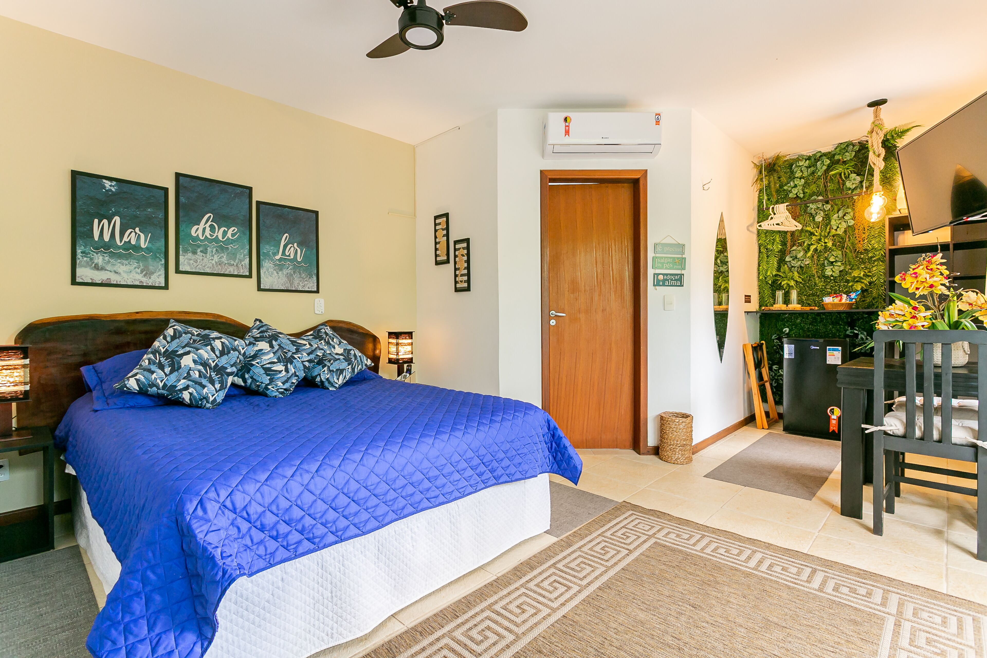 A bedroom with a large bed, a wooden headboard, a ceiling fan, and a wall-mounted air conditioner.