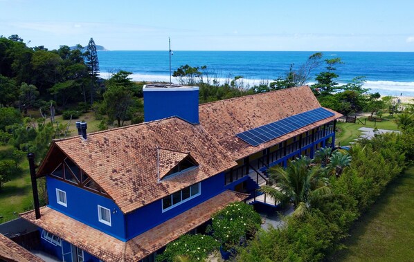 A large house with a tiled roof, solar panels, and a view of the ocean. - Pénareia Floripa (Florianópolis)