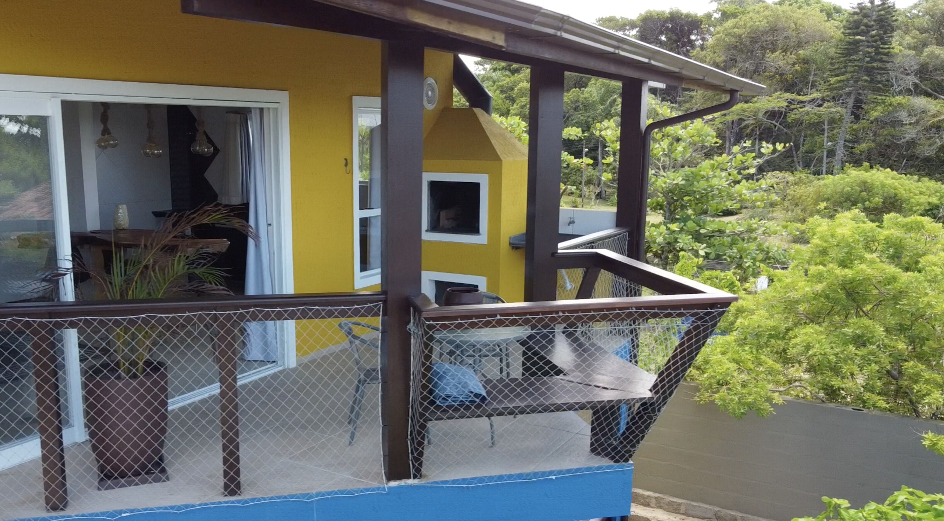 A yellow building with a balcony featuring a mesh railing and a blue floor.