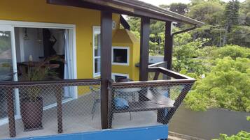 A yellow building with a balcony featuring a mesh railing and a blue floor.