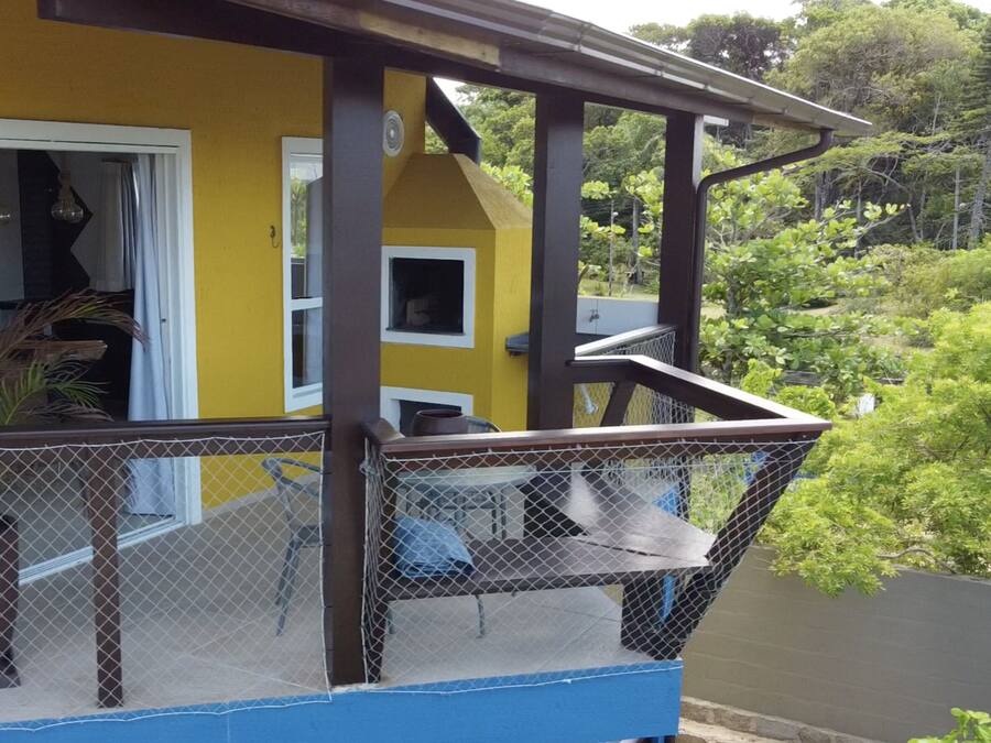 A yellow building with a balcony featuring a mesh railing and a blue floor.