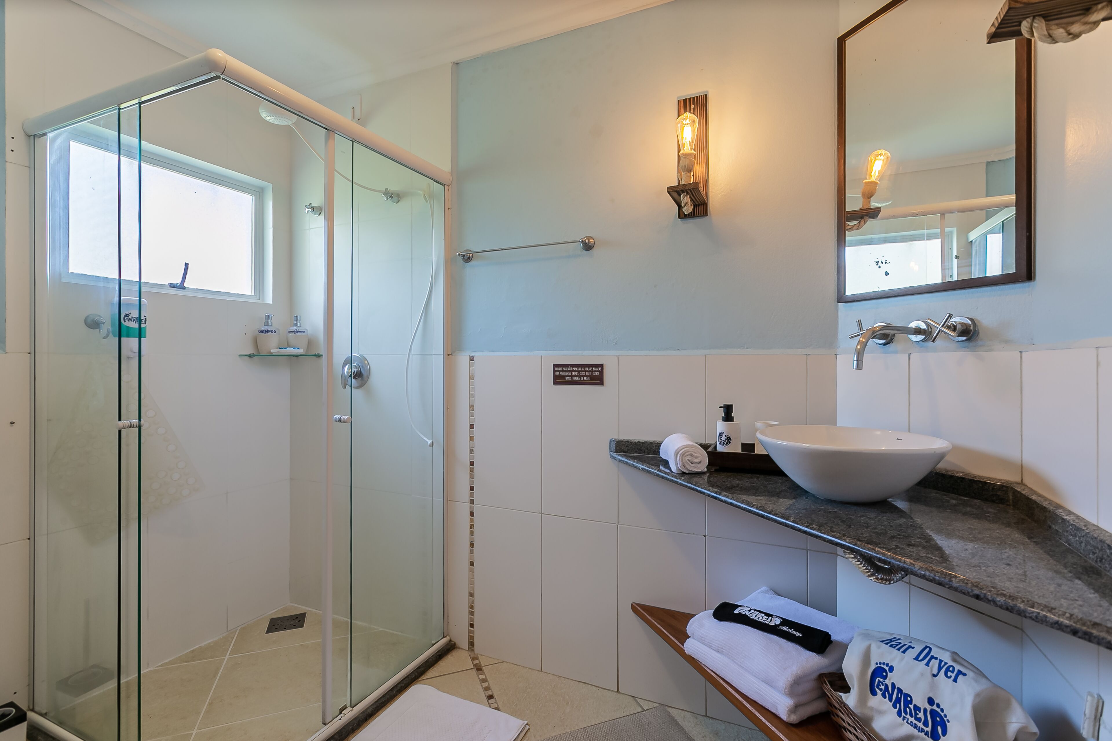 A modern bathroom with a glass shower enclosure, a white sink, and a towel rack.