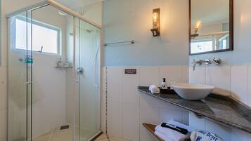 A modern bathroom with a glass shower enclosure, a white sink, and a towel rack.