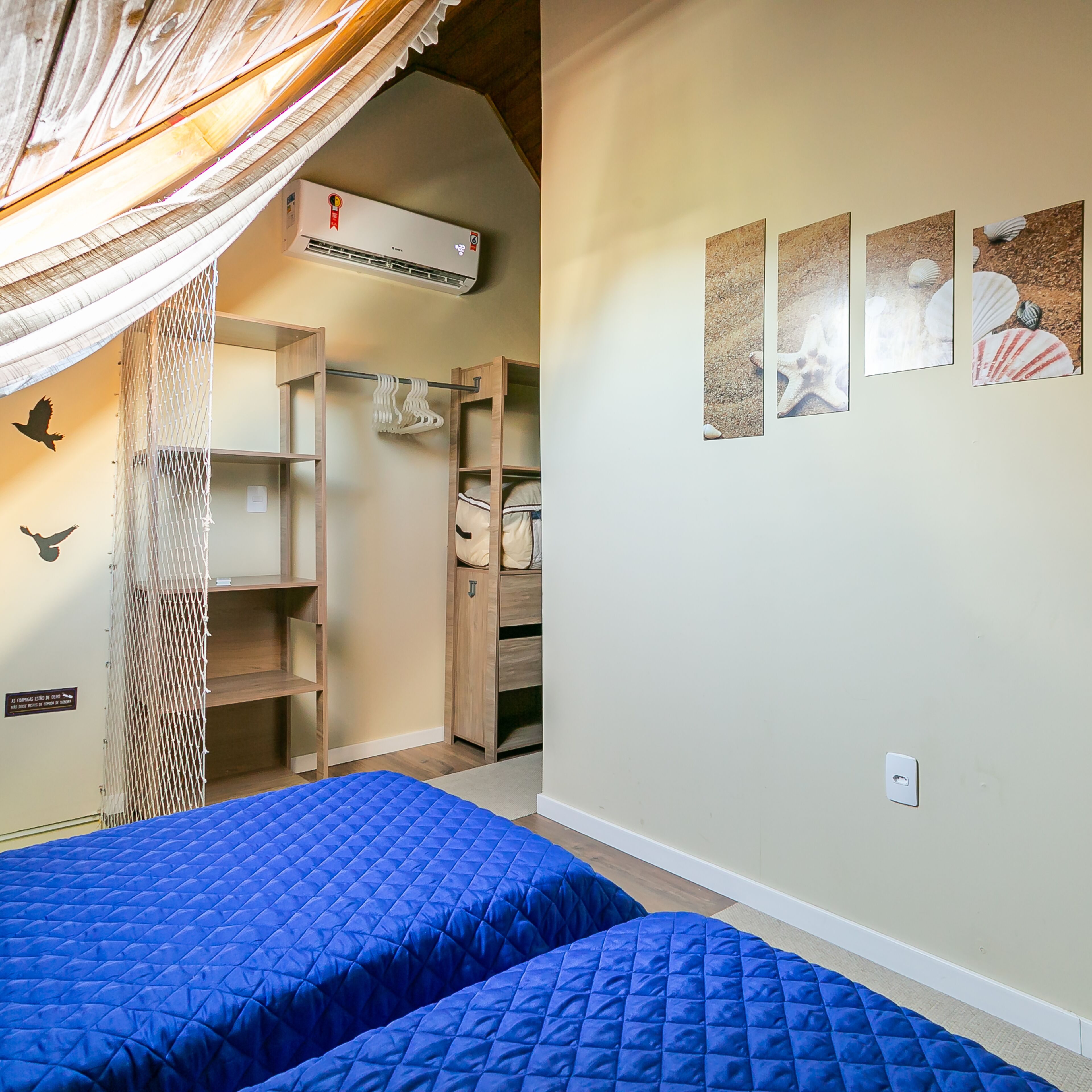 A bedroom with two beds, a wardrobe, and a hanging chair.