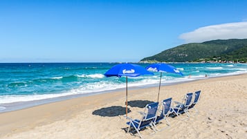 Na praia, areia branca, guarda-sóis, toalhas de praia 