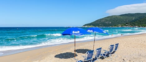 På stranden, vit sandstrand, parasoller och strandhanddukar