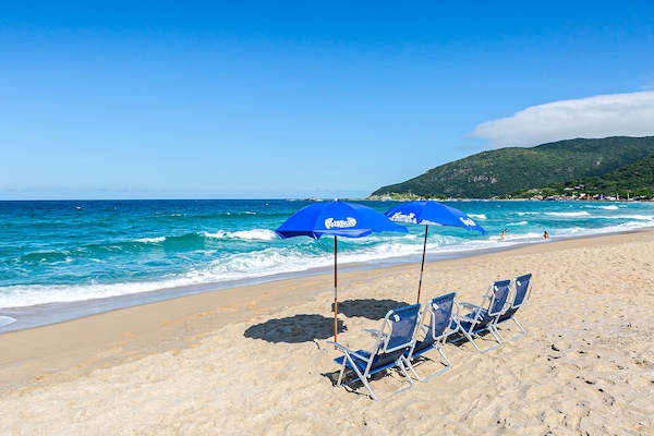 Na praia, areia branca, guarda-sóis, toalhas de praia