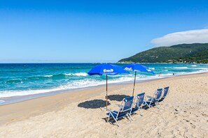 Na praia, areia branca, guarda-sóis, toalhas de praia 