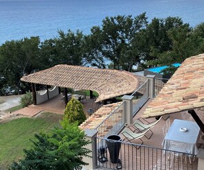 Un patio con techo curvo, mobiliario exterior y vista al océano.